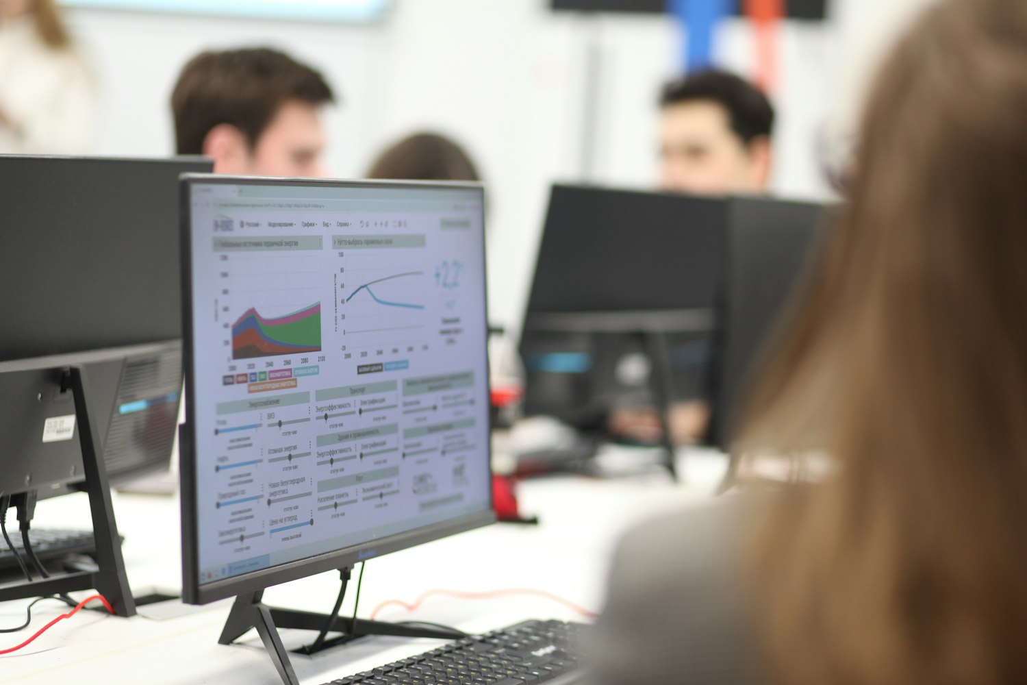 Persona analizando tableros de datos y gráficos en la pantalla de una computadora en una oficina