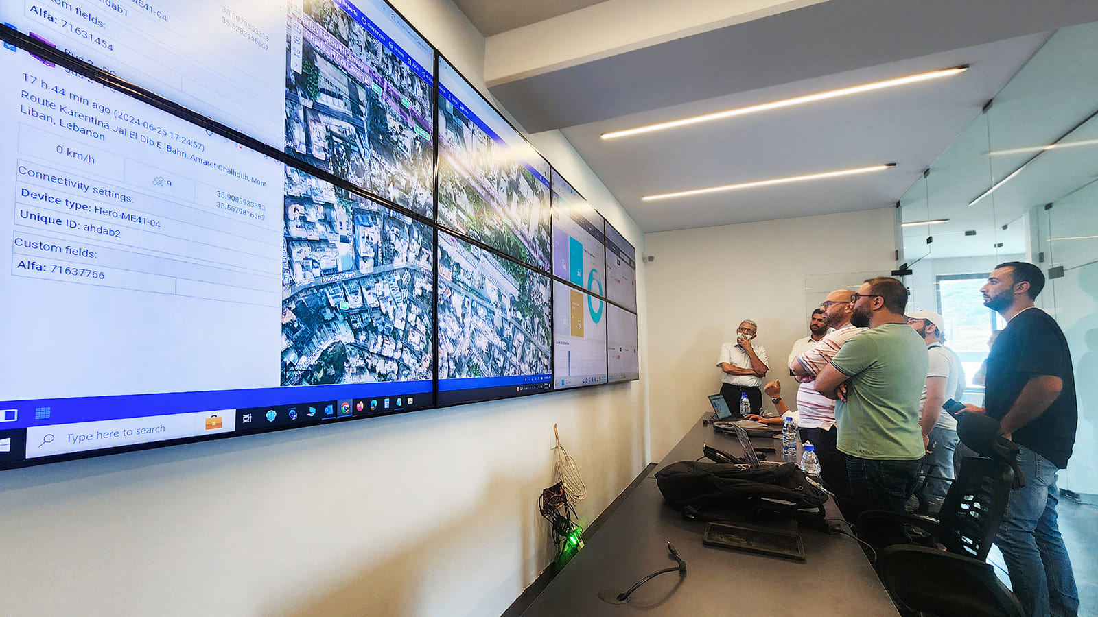 Sala de control con una pared de pantallas y un grupo de personas mirando los tableros