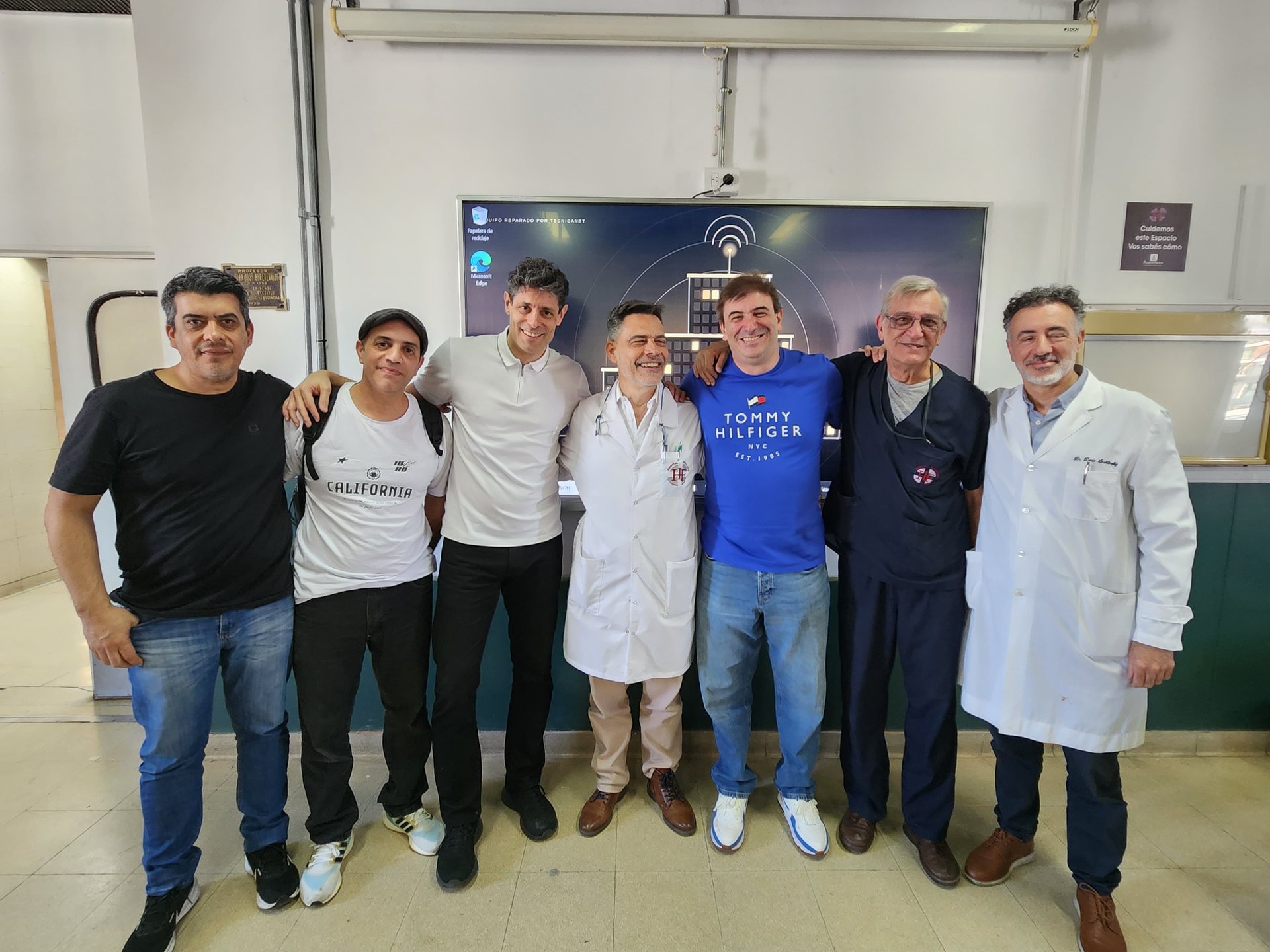 Equipo de Tecnicanet junto al personal del Hospital Fernández frente a la pantalla reparada